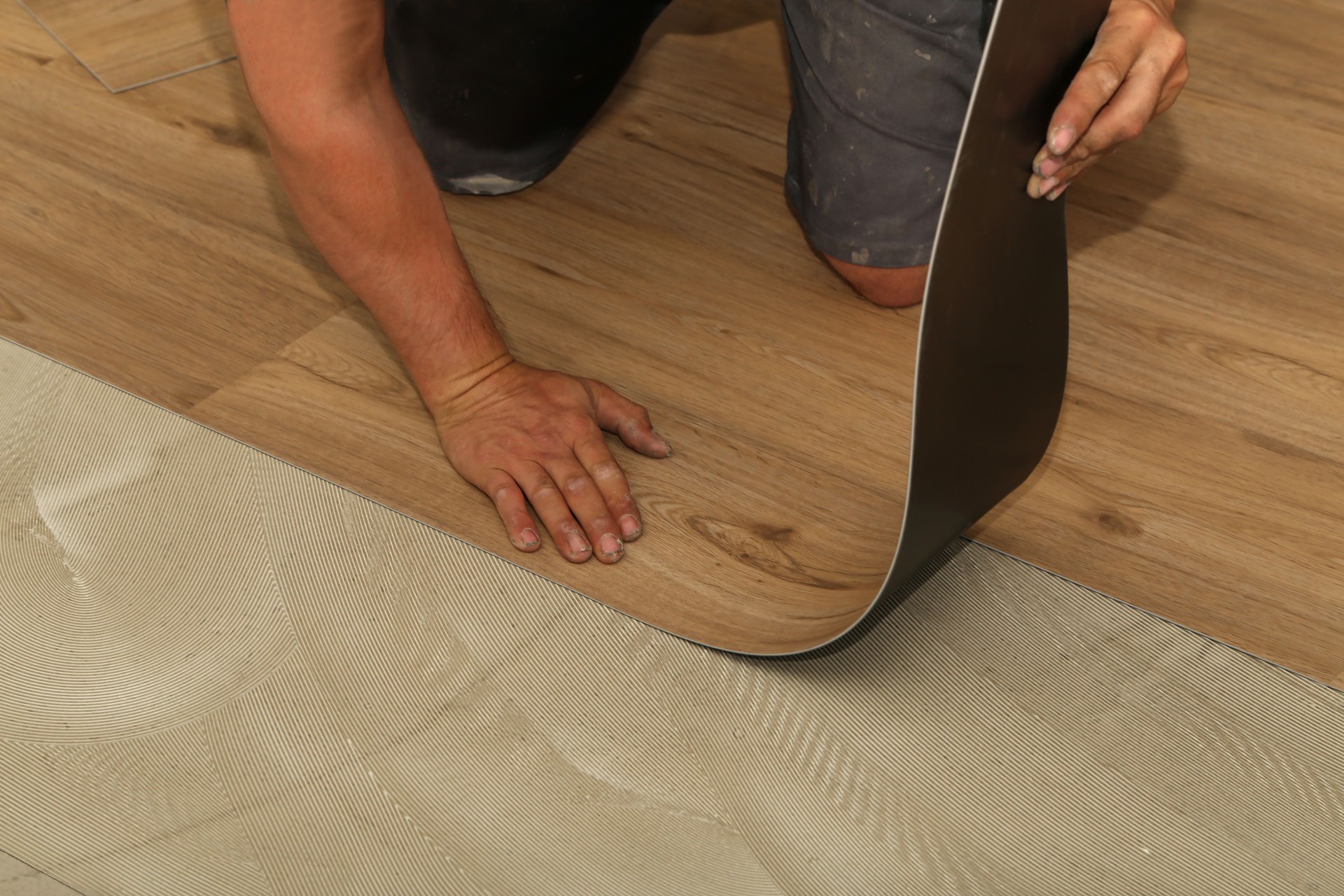 The worker installing new vinyl tile floor